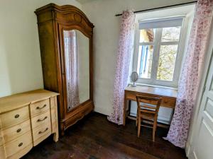 Jumilhac-le-GrandSous le Chateau的一间卧室配有梳妆台、镜子和窗户。