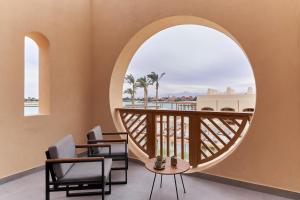 赫尔格达艾高娜施泰根博阁高尔夫度假酒店的客房设有带椅子的阳台和圆形窗户。