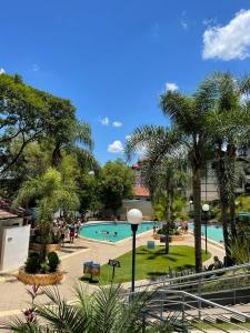 皮拉图巴Casa das Bromélias- Com Quiosque em meio à natureza!的棕榈树泳池和公园里的人