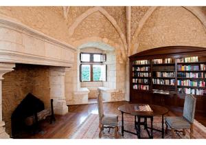 ChabenetHapimag Château de Chabenet的一间设有壁炉和图书馆内一张桌子的房间