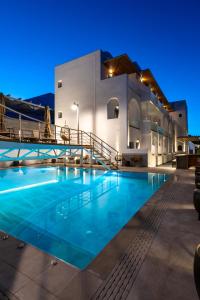 费拉Deluxe Hotel Santorini的夜间在房子前面的游泳池