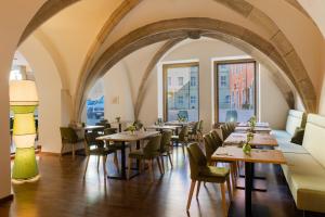 雷根斯堡Altstadthotel Arch的餐厅设有桌椅和窗户。