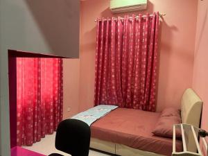 哥打巴鲁Homestay Rohmat的一间卧室配有红色窗帘和一张带椅子的床