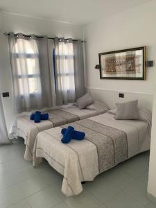 马斯帕洛马斯Dúplex Maspalomas的客房内的三张床和蓝色枕头
