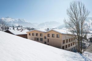 格施塔德格施塔德萨嫩兰德青年旅舍的一座位于一座白雪覆盖的山丘上的建筑,山丘背景是山丘