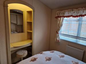 牛顿斯图尔特Castlewigg holiday park Whithorn 2 bed caravan的一间卧室配有一张床、镜子和窗户