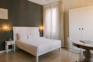 威尼斯Salute Palace powered by Sonder的卧室配有白色的床和书桌