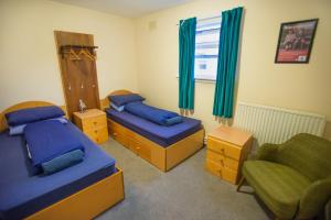 柯克沃尔Kirkwall Youth Hostel的一间卧室设有两张床、一把椅子和一个窗户。