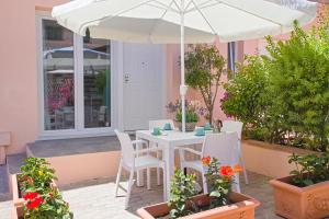 费拉约港Appartamenti Mare Portoferraio的庭院的遮阳伞下的白色桌子和椅子
