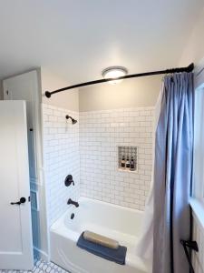 普尔曼State Street Cottage, Suite 2的带浴缸和蓝色淋浴帘的浴室