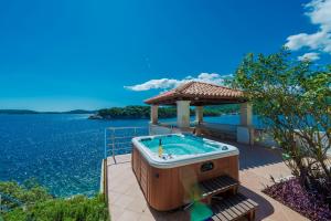 杜布罗夫尼克Villa Vacanza Dubrovnik - Five Bedroom Villa with Private Sea Access的水边的天井上的热水浴池