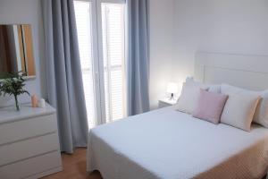 贝莱斯Niza Mar的白色卧室配有白色床和粉红色枕头