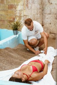 伊斯基亚Hotel Ferdinando Beach & Thermal Spa的坐在女人旁边躺在地上的男人