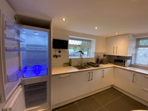 兰鲁斯特Modern 4-bed Cottage Llanwrst Town Centre & Parking - Snowdonia! near Betws-y-Coed的厨房配有白色橱柜和大冰箱。