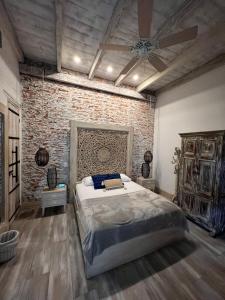 卡利MAHI CASA BOUTIQUE的一间卧室设有一张大床和砖墙