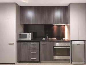 悉尼悉尼机场阿迪纳公寓式酒店的厨房配有不锈钢用具和微波炉