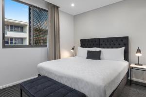 悉尼赖德北梅里顿公寓式酒店的一间卧室设有一张大床和一个窗户。