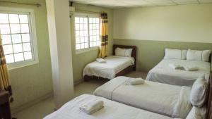 博卡斯德尔托罗Hotel Cristina的客房设有三张床、白色床单和窗户。