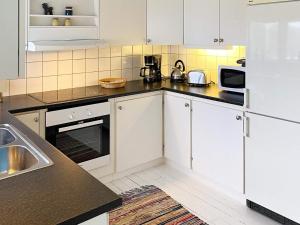 OdensbackenHoliday home ODENSBACKEN III的厨房配有白色橱柜和黑色台面