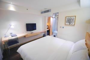 台中市碧根逢甲酒店的酒店客房配有一张床、一张书桌和一台电视。
