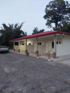 Kuala PenyuMargereth Cottage的一座红色屋顶的建筑和一个停车场