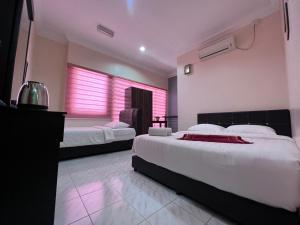克提HOTEL RAUDHAH Kerteh的配有粉红色灯的客房内的两张床