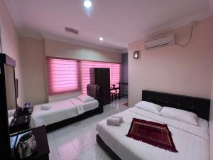克提HOTEL RAUDHAH Kerteh的酒店客房设有两张床和一张桌子。
