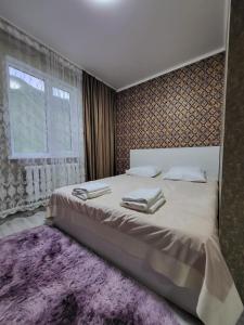 KurmentyКольсайские озера, гостиница Айару的一间卧室配有一张大床和紫色地毯