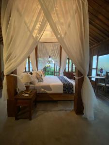 博拉巴图Sarini Villas的一间卧室配有一张天蓬床和一张桌子