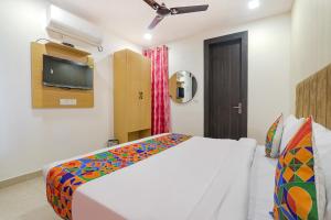 PrayagrajFabHotel The Comfort的卧室配有一张床,墙上配有电视。