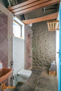 浦那Ekayana Resorts and Agri Tourism, Mulshi的一间带卫生间和石墙的浴室