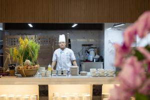 芽庄Miracle Luxury Nha Trang的厨师站在厨房的柜台后面