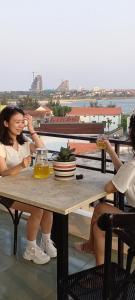 洞海Tan Hoang Minh Hotel的两个女人坐在桌子边喝一杯