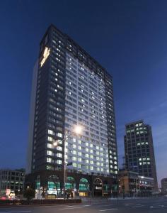 釜山釜山皇冠海港酒店的一座高大的建筑,晚上在城市里亮着灯