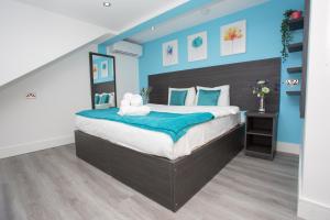 斯劳Heathrow Windsor Apart Hotel的一间卧室配有一张带蓝色墙壁的大床