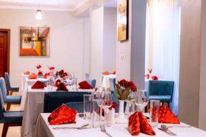 基加利传奇精品酒店 的一间设有白色桌子和红色餐巾的用餐室