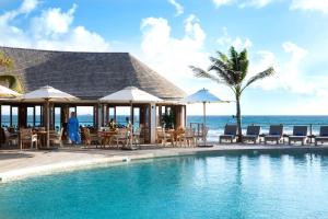 古斯塔维亚Hotel Manapany的一个带桌椅的游泳池以及大海