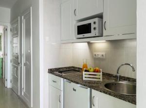 科拉雷侯Apartamentos Hesperia Bristol Playa的白色的厨房配有水槽和微波炉