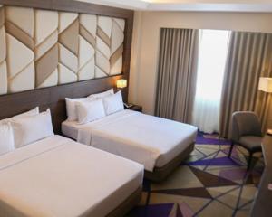 马尼拉鲁克森特酒店的酒店客房,配有两张床和椅子