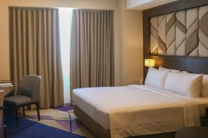 马尼拉鲁克森特酒店的酒店客房带一张大床和一把椅子