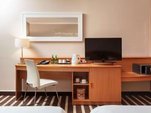 波兹南诺富特波兹南中心酒店的客房设有书桌、电视和椅子