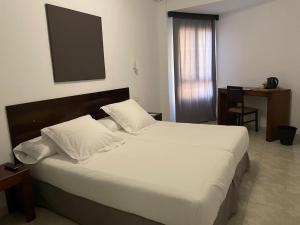 洛斯·亚诺斯·德·阿里丹维莱阿里达内酒店的一间卧室配有一张带白色床单的大床