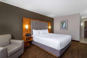 圣约翰堡Ramada by Wyndham Northern Grand Hotel & Conference Centre的酒店客房带一张大床和一把椅子