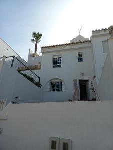阿尔姆尼卡Casa Gran Tropicana playa a 2 minutos.的一座白色的房子,后面有棕榈树