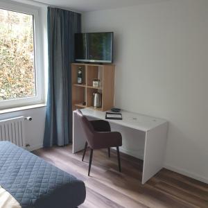 格明德Kurparkhotel-Gemünd的客房设有一张桌子、一把椅子和一台电视