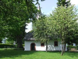 黑伦塔尔Gästehaus Jütten的草丛中树木的白色小房子