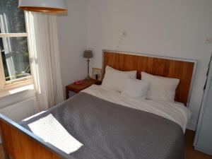 斯霍尔Duinappartementen Schoorl的一间卧室配有一张带木制床头板的床和窗户。
