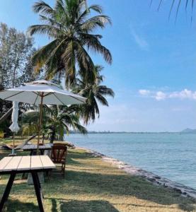 瑶亚岛Koh Yao Yai Sea Breeze House เกาะยาวใหญ่ซีบรีซเฮ้าส์的海滩上设有桌子和遮阳伞,海洋