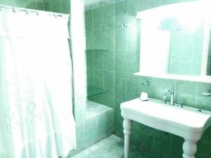 圣米格尔·德·图库玛CASA QUINTA LA ENCANTADA的绿色瓷砖浴室设有水槽和淋浴