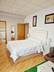 科尔多瓦Hostal El Brillante - Alojamientos El Duque的一间白色的大卧室,配有一张大床和椅子